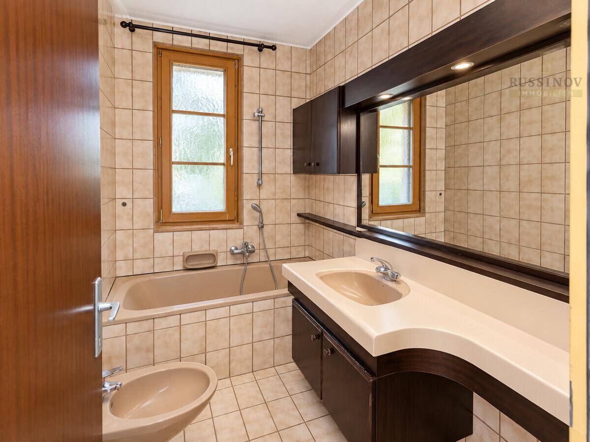 Badezimmer im Stil der 80er Jahre mit Badewanne, Bidet und großem Spiegel.