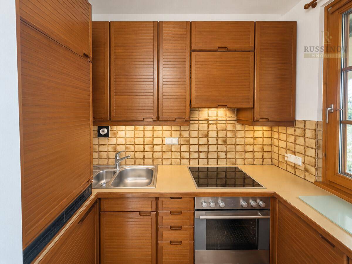 Funktionale Küche mit Holzfronten, gefliestem Fliesenspiegel und integrierten Geräten.