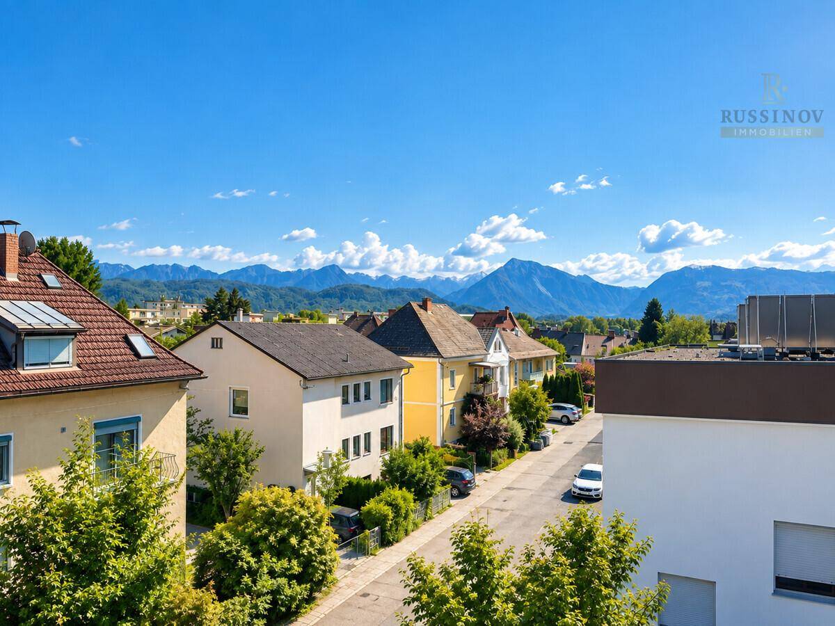 Panoramablick über eine Wohnsiedlung mit Häusern und majestätischen Bergen im Hintergrund.