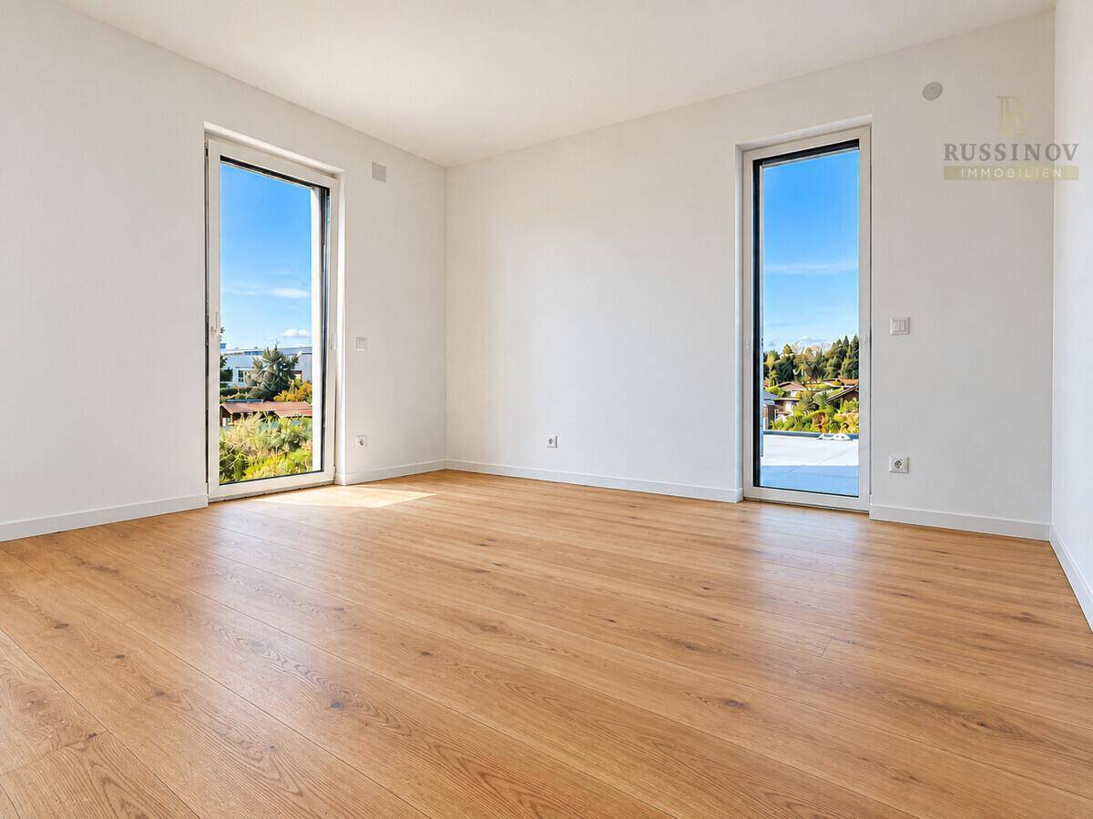 Geräumiges, helles Zimmer mit zwei Fenstern und Holzboden, ideal als Schlafzimmer.