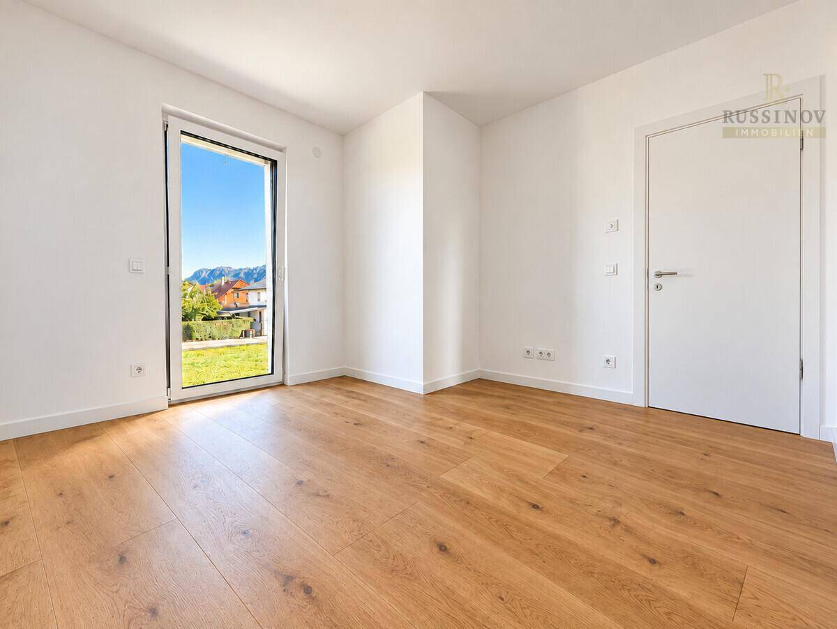 Helles Zimmer mit Holzboden und einem Fenster, das einen schönen Bergblick bietet.