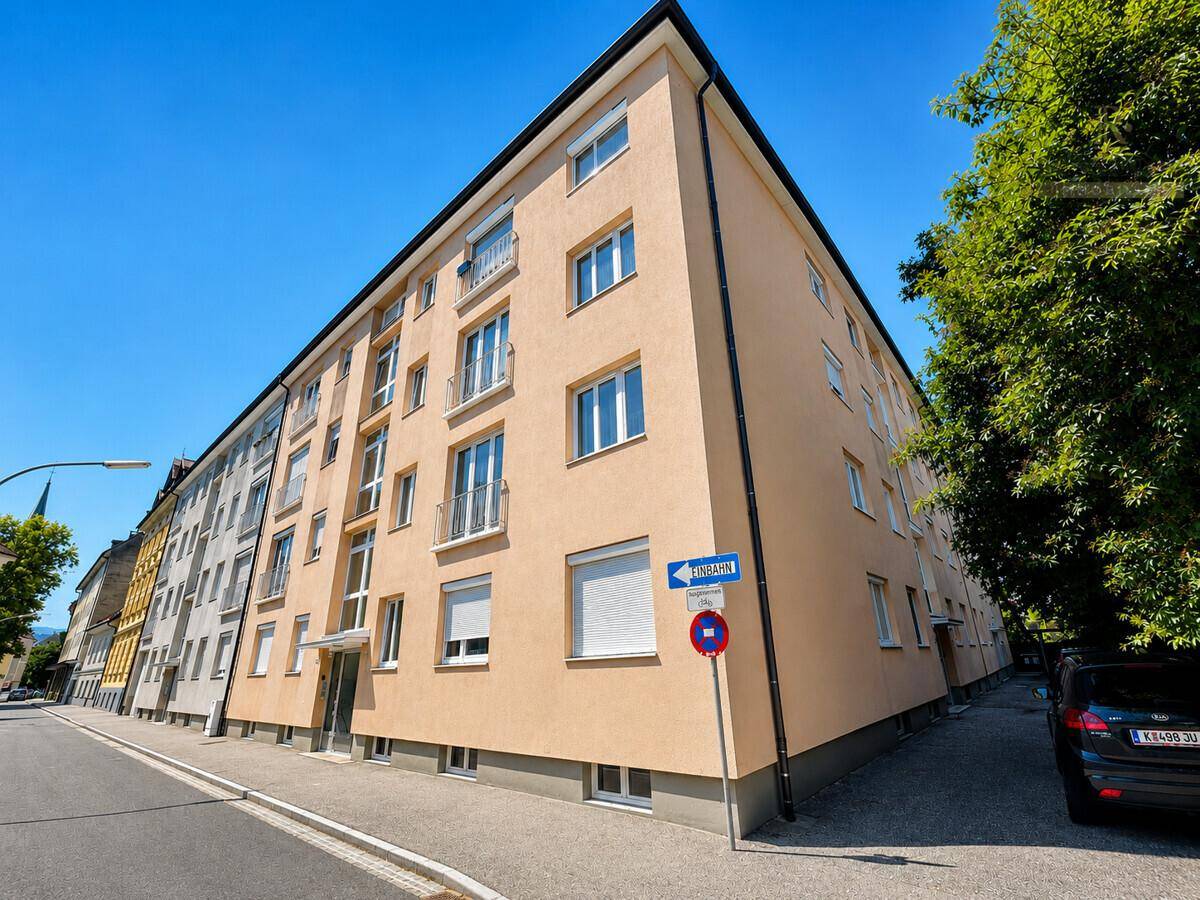 Mehrfamilienhaus mit mehreren Etagen und Balkonen an einer ruhigen Straße gelegen.