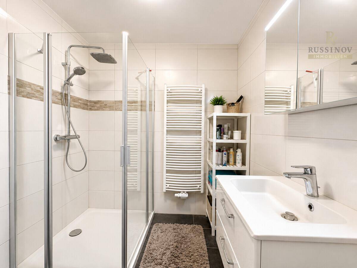Modernes Badezimmer mit ebenerdiger Dusche, Waschtisch und beheiztem Handtuchhalter.