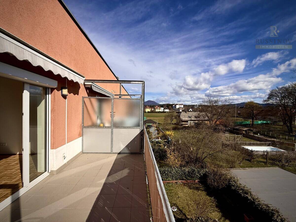 Balkon mit Fliesenboden und Blick auf die grüne Umgebung und einen Pool.