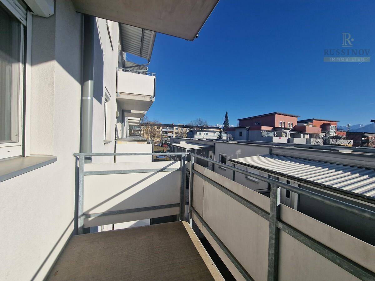 Balkon mit Blick auf die umliegenden Gebäude und die Nachbarschaft unter blauem Himmel.