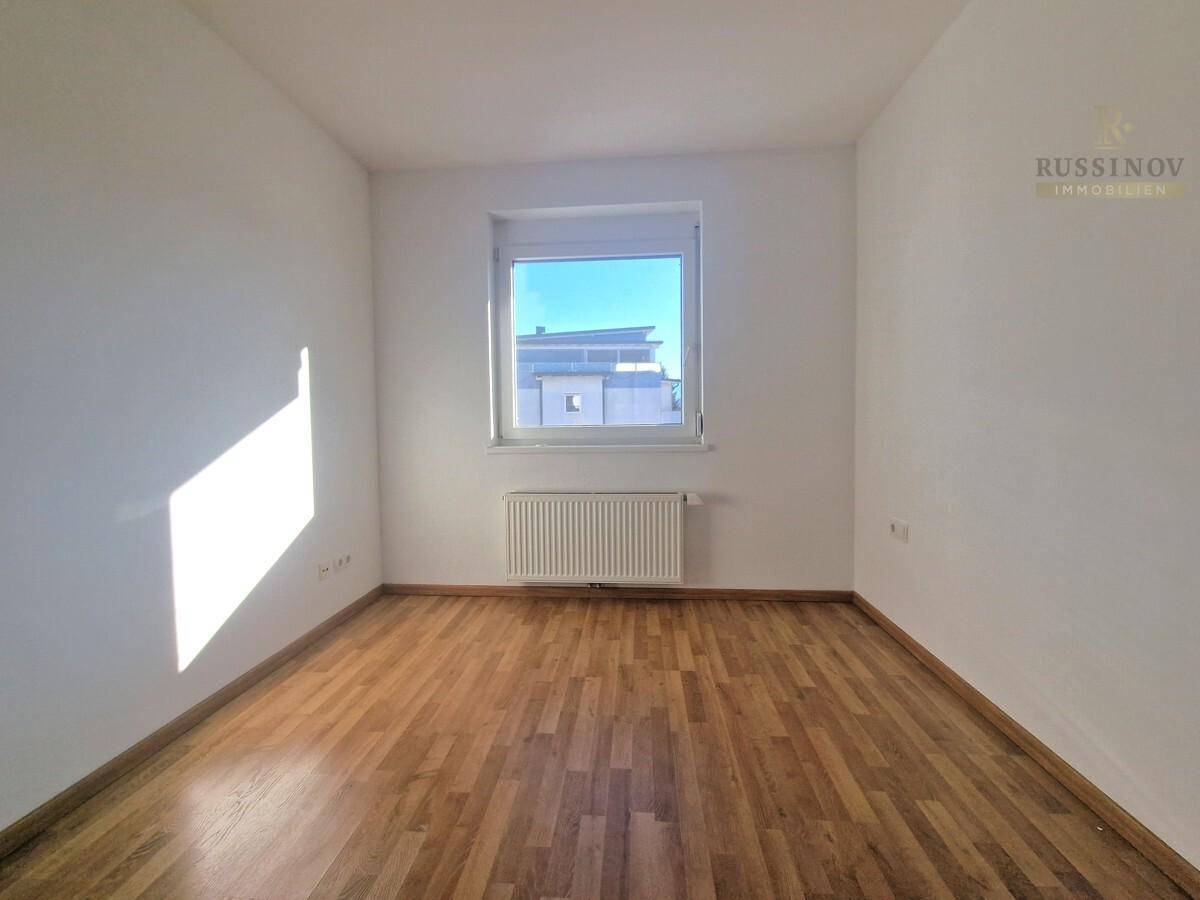 Ruhiges Schlafzimmer mit Holzboden und einem Fenster, das für natürliche Belichtung sorgt.