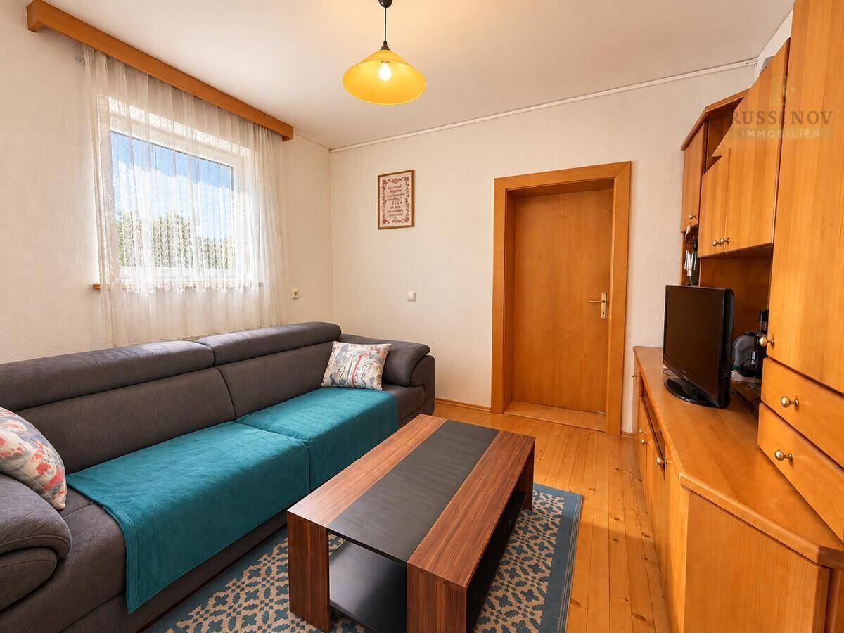 Gemütliches Wohnzimmer mit Holzboden, Sofa und einem kleinen Fernseher.