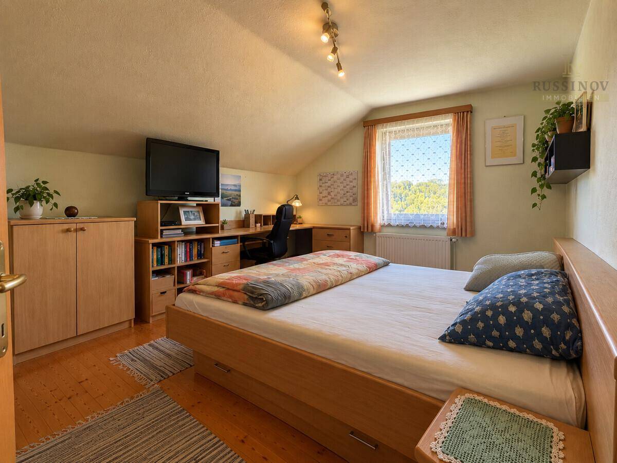 Geräumiges Schlafzimmer im Dachgeschoss mit Holzboden, Schreibtisch und Doppelbett.
