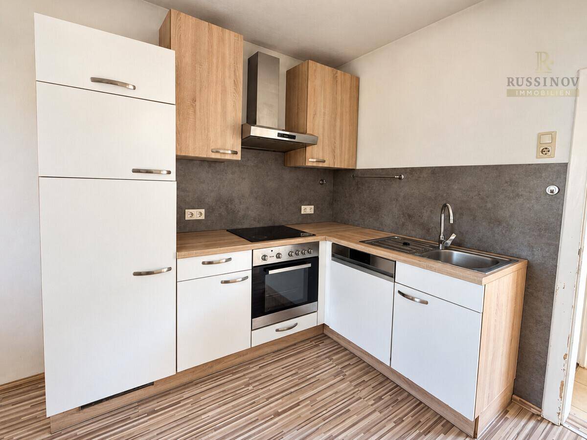Moderne Einbauküche mit hellen Holz- und weißen Fronten sowie Induktionskochfeld.