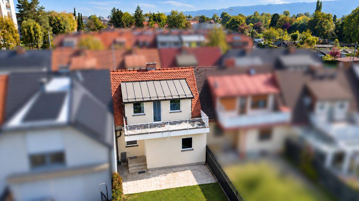 Luftaufnahme eines Reihenhauses mit Balkon und Gartenbereich.