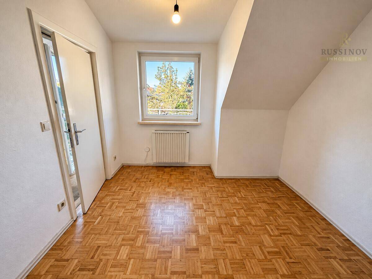 Helles Schlafzimmer mit Parkettboden und Dachschräge.