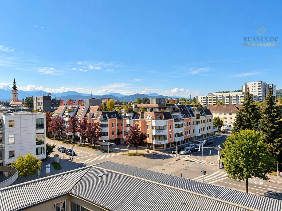 Panoramablick über die Stadt mit Gebäuden, Straßen und majestätischen Bergen im Hintergrund.
