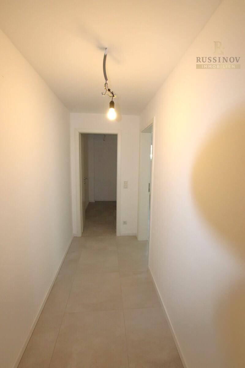 Heller Flur mit Fliesenboden und Zugang zu weiteren Räumen im Haus.