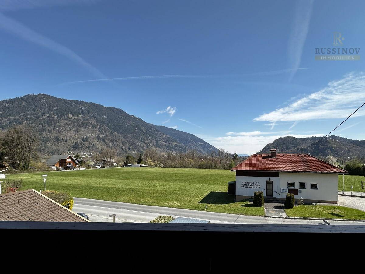 Weitläufiger Blick über grüne Felder und Berge unter blauem Himmel.
