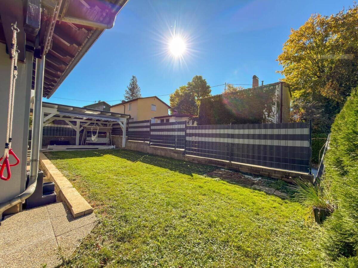 Sonnige Rasenfläche im Garten mit Blick auf die umliegenden Häuser und Bäume.