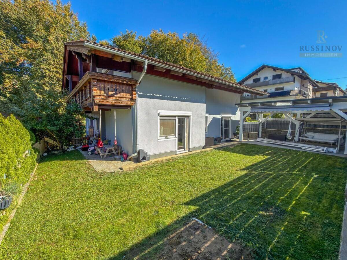 Rückansicht des Hauses mit großem Garten, Rasenfläche und überdachtem Freisitz.