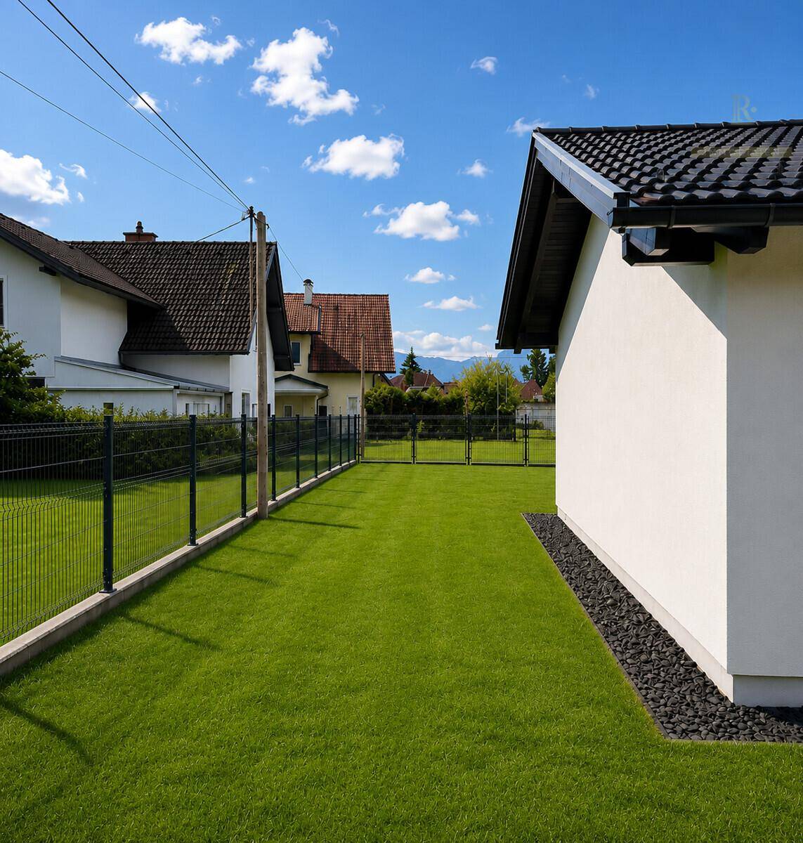 Gepflegter Gartenbereich mit Rasenfläche und Zaun, umgeben von ländlicher Idylle.