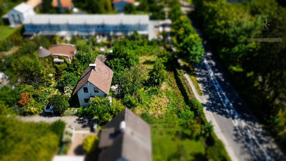 Übersicht aus der Vogelperspektive mit Wohnhaus, viel Grün und angrenzender Straße.