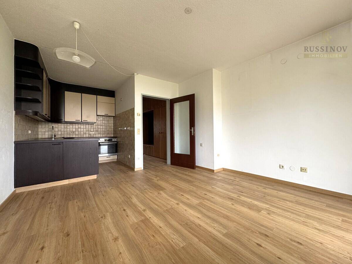 Heller Wohnbereich mit funktionaler Küchenzeile und Laminatboden, bereit zur individuellen Gestaltung.