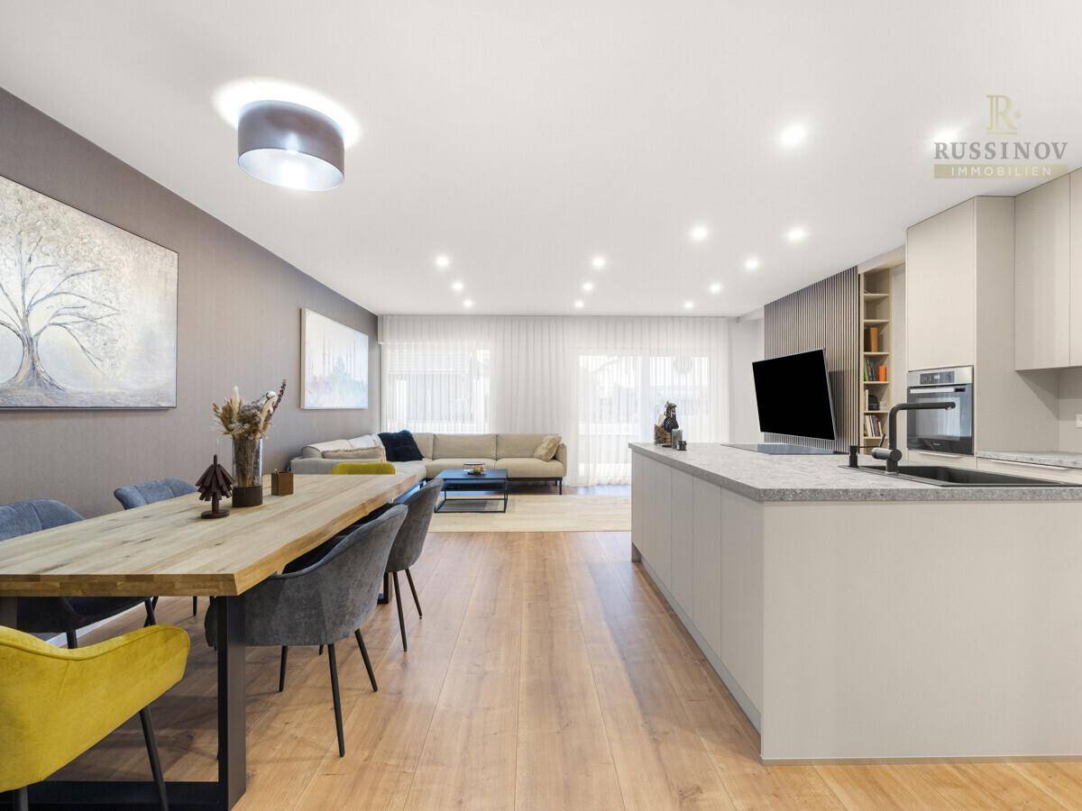 Heller Wohnbereich mit offener Küche, Essbereich und großen Fenstern für viel Tageslicht.