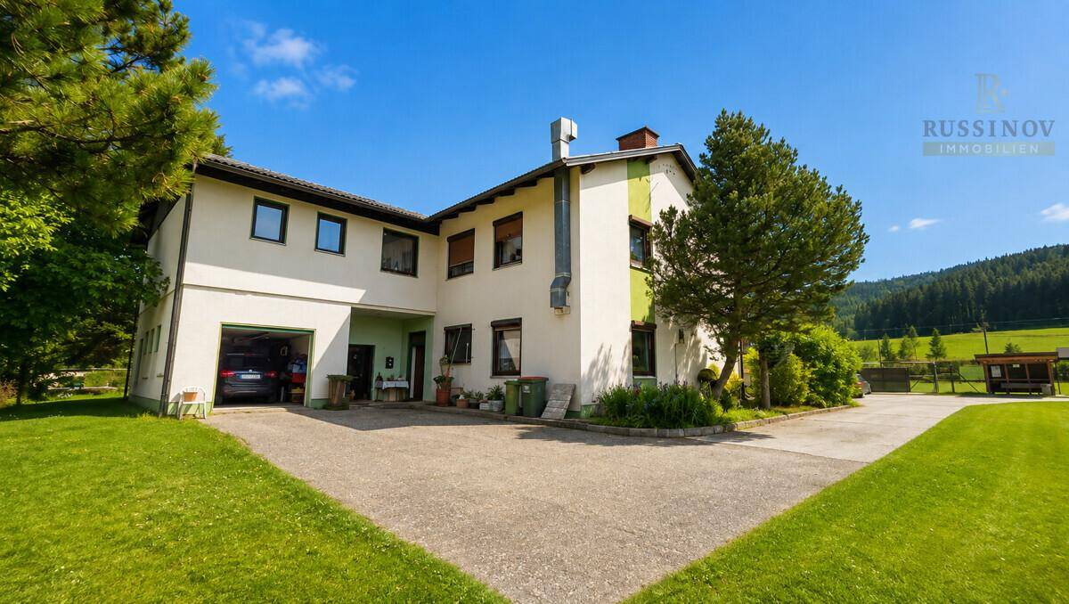 Rückansicht des Hauses mit Garage, großem Garten und einer weiten ländlichen Umgebung.