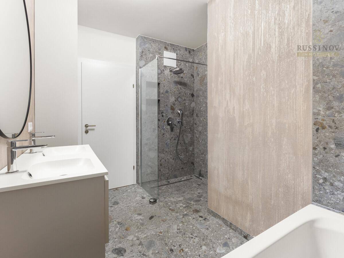 Geräumiges Badezimmer mit begehbarer Dusche, Doppelwaschbecken und modernen Fliesen.