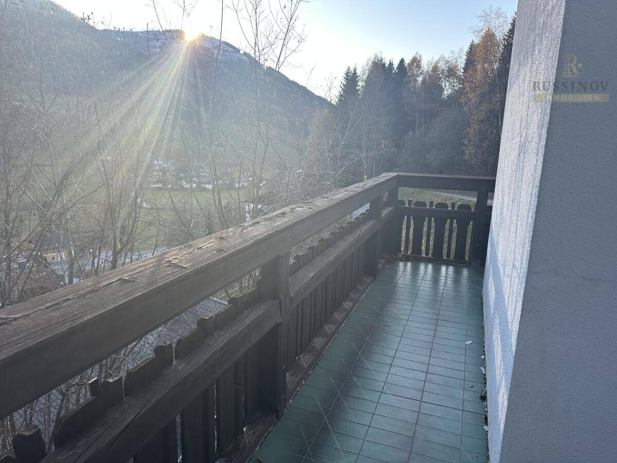 Balkon mit Holzbalken und Fliesenboden, bietet einen weiten Blick auf die Berge.