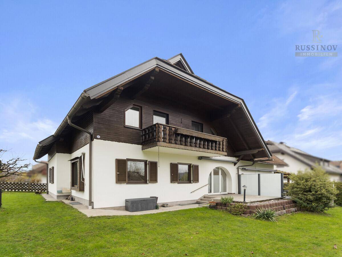 Rückansicht des Hauses mit Balkon, kleiner Terrasse und Gartenbereich.