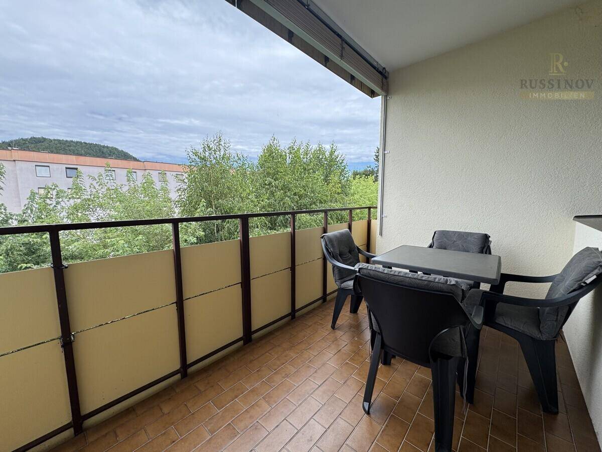 Möblierter Balkon mit Fliesenboden und Blick ins Grüne, ideal für entspannte Stunden im Freien.