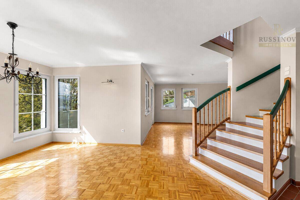 Heller Wohnbereich mit Parkettboden und eleganter Holztreppe zum Obergeschoss.