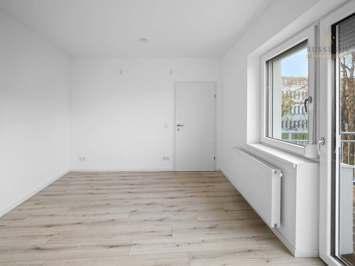 Geräumiges, helles Zimmer mit Laminatboden und großem Fenster, bereit zur individuellen Gestaltung.