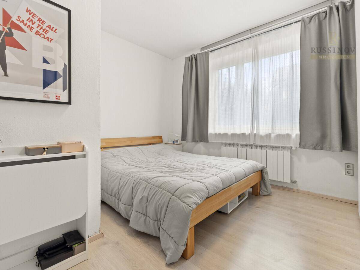 Schlafzimmer mit Holzbett, Holzboden und großem Fenster für viel Tageslicht.