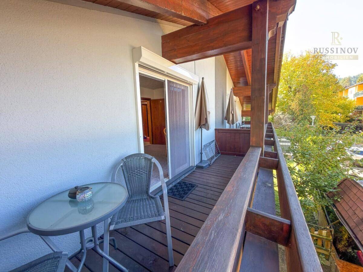 Gemütlicher Holzbalkon mit Sitzgelegenheiten und Blick auf die grüne Umgebung.