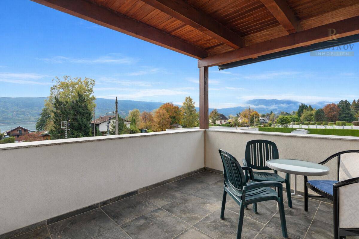 Überdachter Balkon mit Sitzgelegenheiten und weitem Blick auf die Landschaft und die Berge.