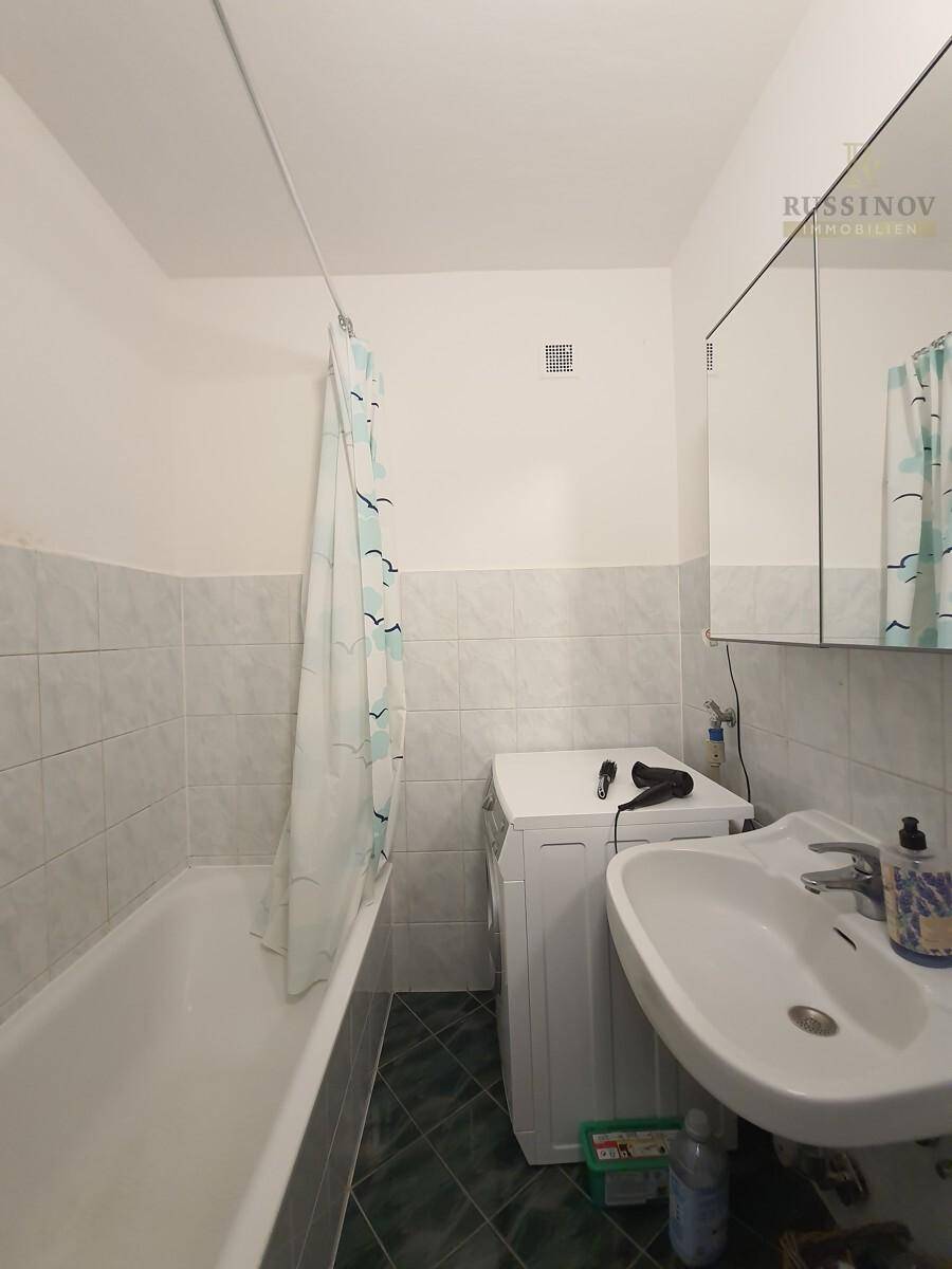 Badezimmer mit Badewanne, Duschvorhang, Waschbecken und Spiegelschrank.