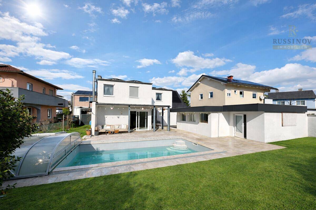 Weitläufiger Gartenbereich mit Swimmingpool, großer Terrasse und Blick auf die Nachbarschaft.