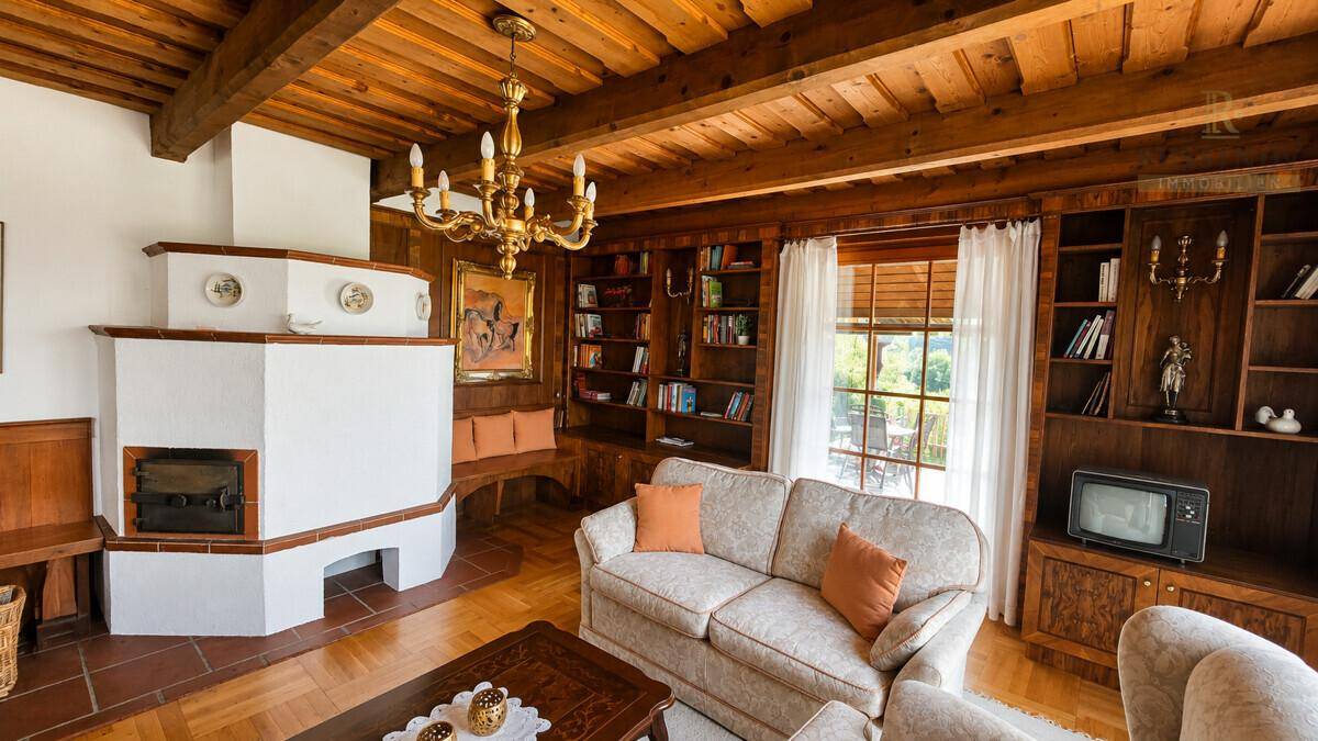 Gemütliches Wohnzimmer mit Kachelofen, Holzbalkendecke und eingebauten Bücherregalen.