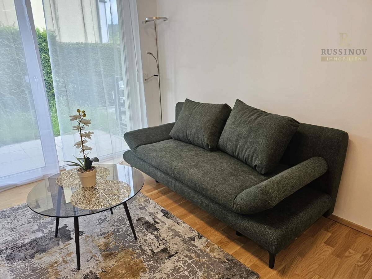 Gemütlicher Wohnbereich mit modernem Sofa, Couchtisch und Zugang zur Terrasse.