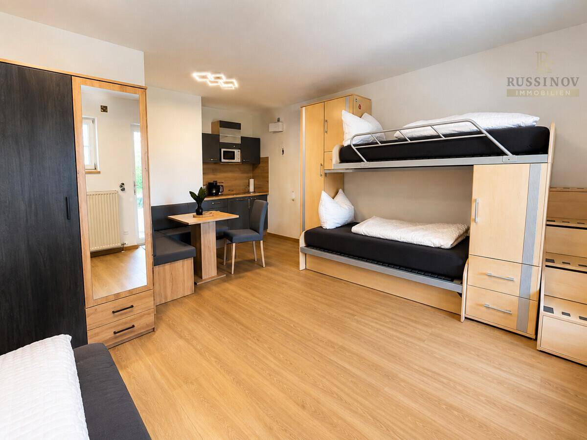 Funktionales Studio-Apartment mit Etagenbett, Essbereich und kompakter Küchenzeile.