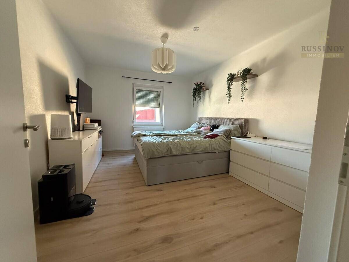 Helles Schlafzimmer mit Doppelbett, weißen Kommoden und Laminatboden.