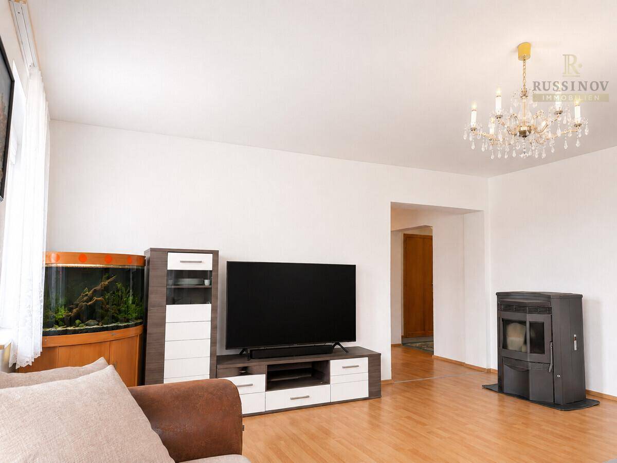 Wohnzimmer mit modernem TV-Möbel, Aquarium und einem gemütlichen Holzofen.