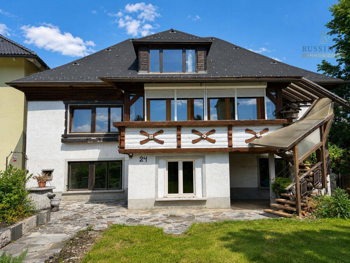 Rückansicht des Hauses mit einem überdachten Balkon und Rollläden an den Fenstern.