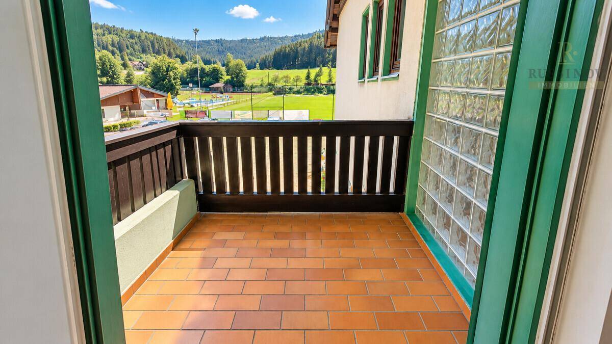 Balkon mit Terrakotta-Fliesen und Holzbalken, bietet einen weiten Blick auf die grüne Umgebung.