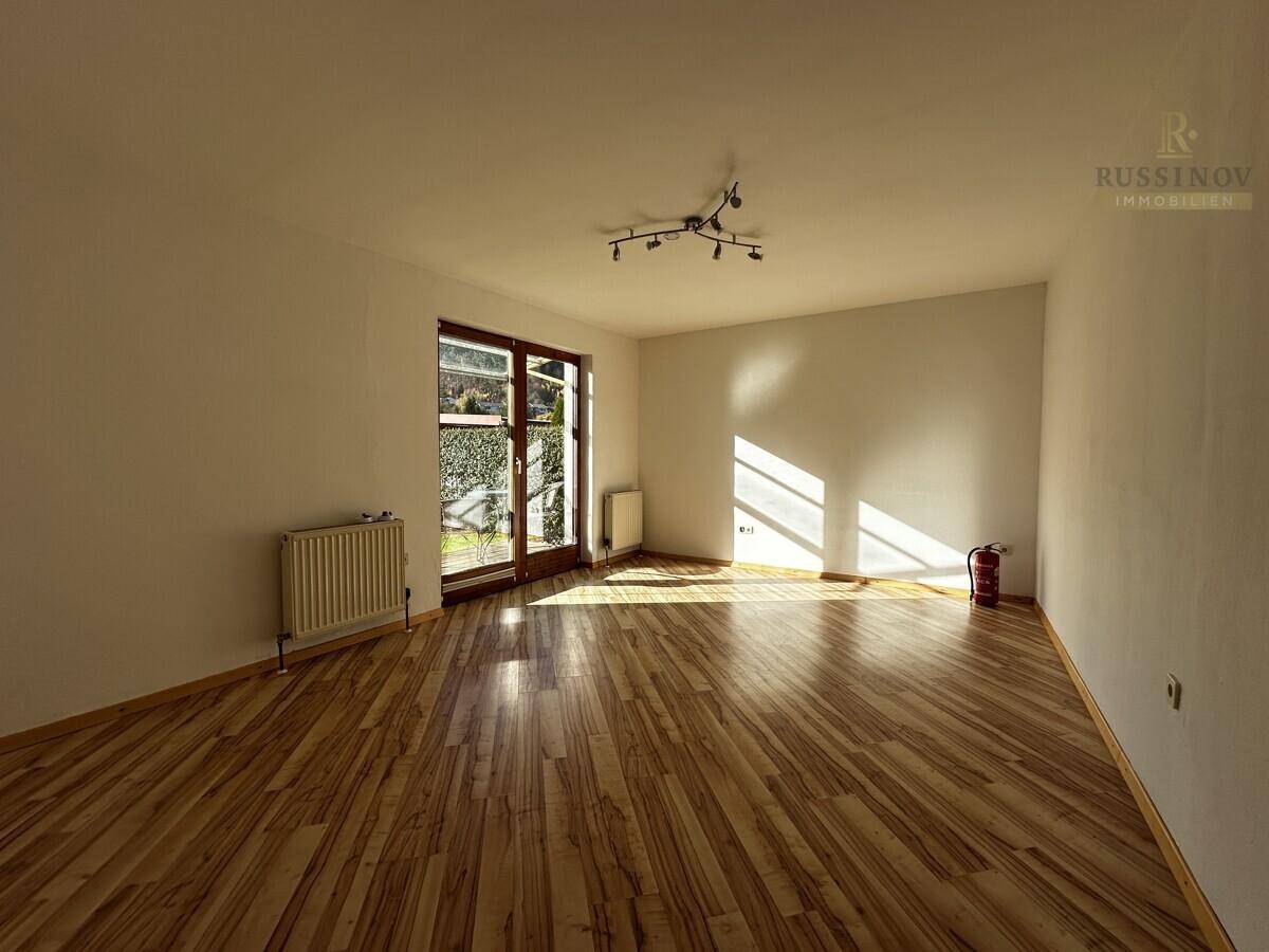 Geräumiges Wohnzimmer mit Holzboden, viel Sonnenlicht und Zugang zum Garten.
