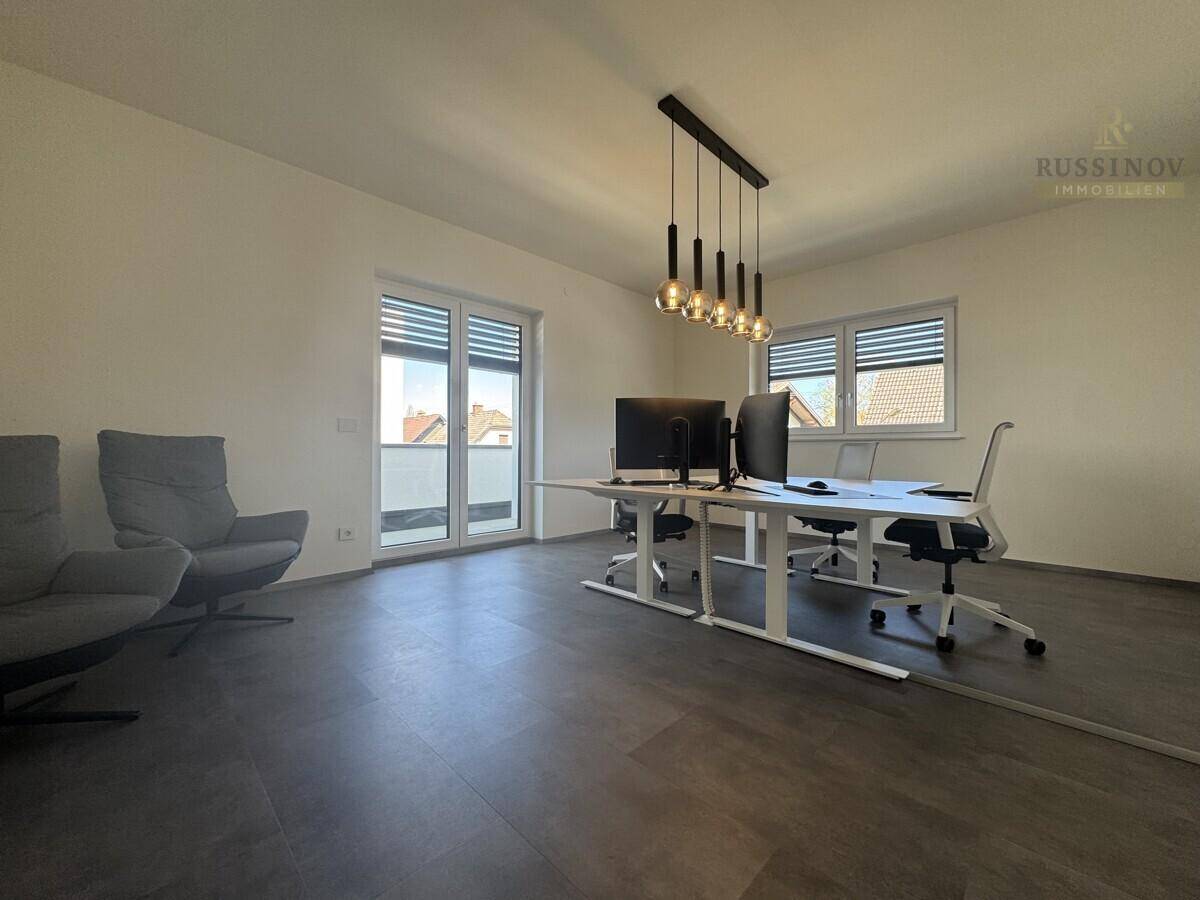 Helles Büro mit dunklem Boden, modernen Möbeln und Zugang zu einem Balkon.