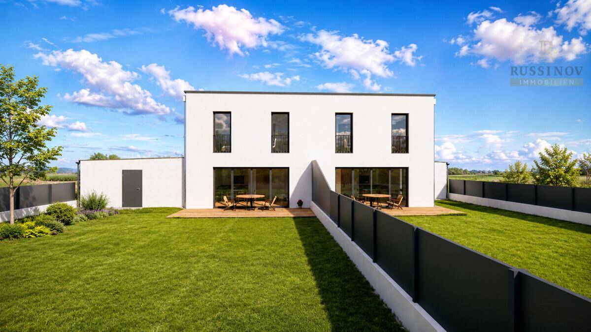 Rückseite des modernen Hauses mit zwei Holzterrassen und weitläufigem Gartenbereich.