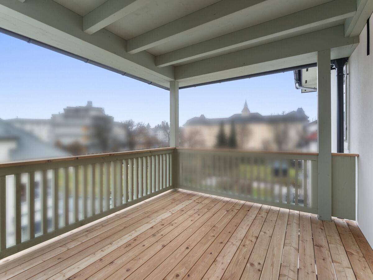 Überdachter Balkon mit Holzfußboden und Blick auf die Umgebung, ideal für entspannte Stunden.