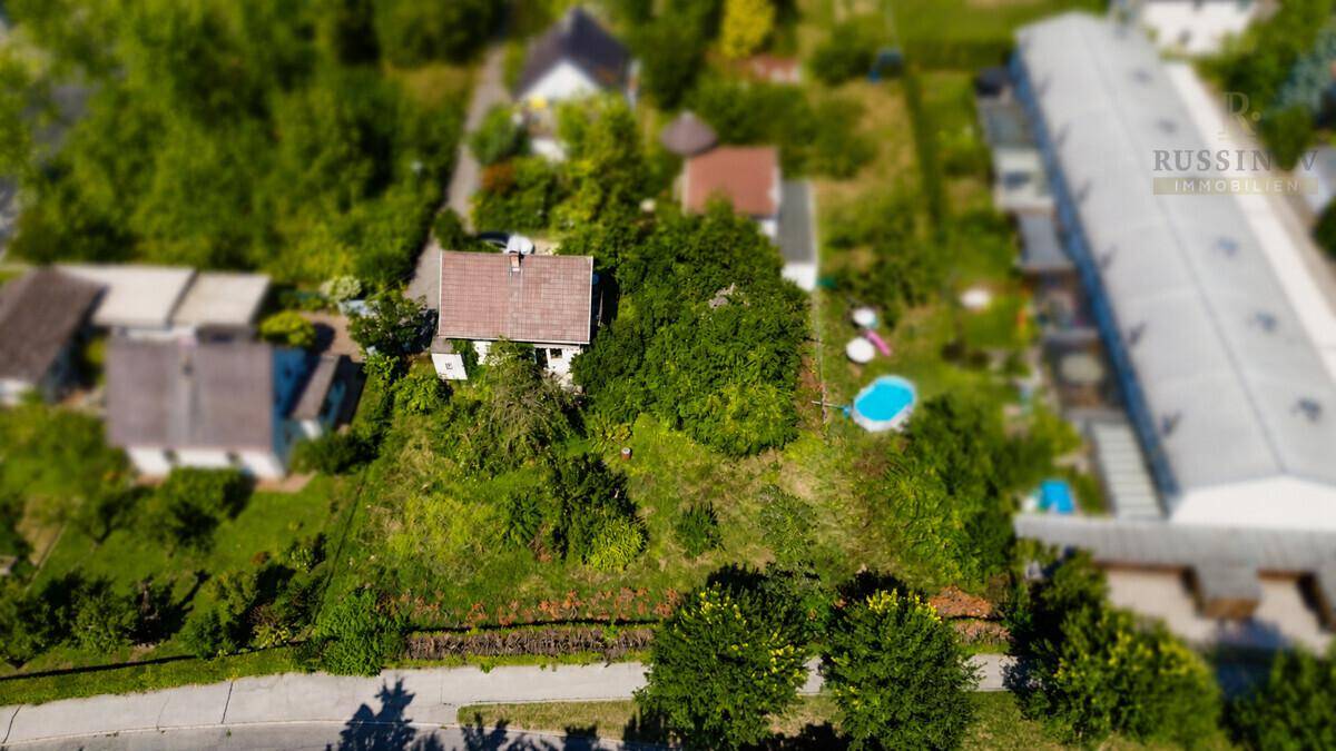 Luftaufnahme eines Grundstücks mit Haus, Bäumen und einem kleinen Pool.