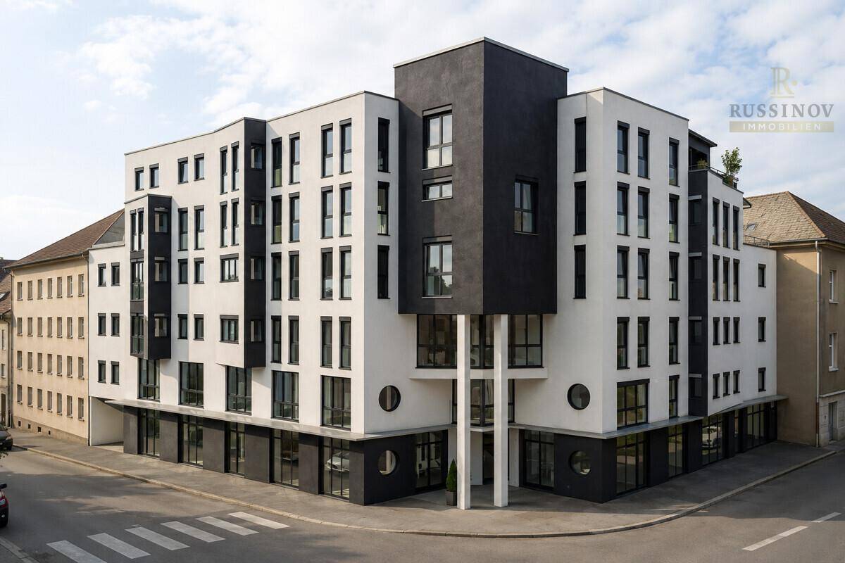 Modernes Geschäftsgebäude mit markanter schwarz-weißer Fassade und großen Fensterfronten an einer Straßenecke.