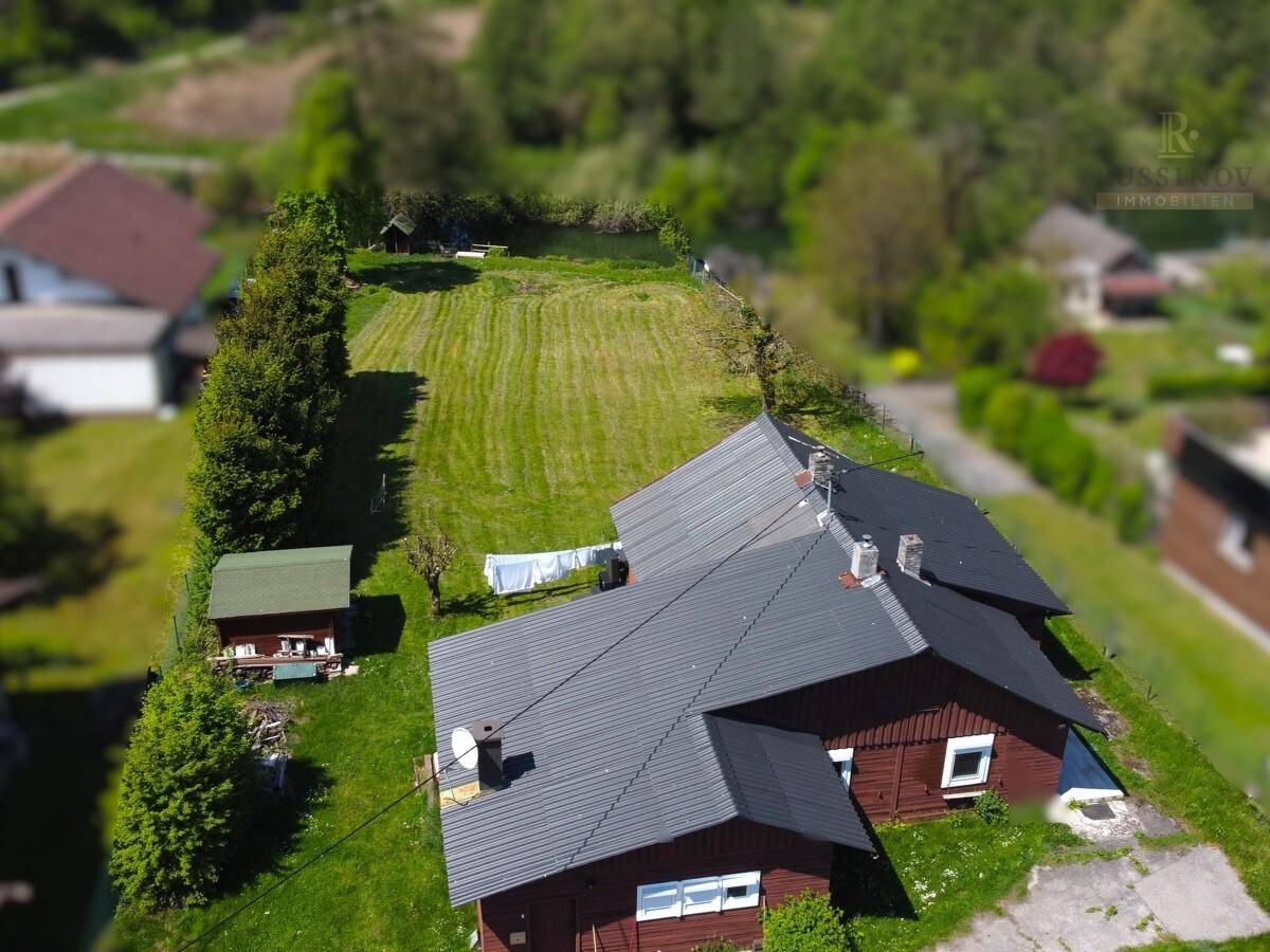 Vogelperspektive des Anwesens mit zwei Gebäuden, einem Gartenschuppen und einer großen Rasenfläche.
